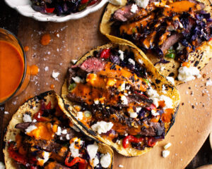 steak tacos with chipotle sauce & roasted cabbage slaw on a board